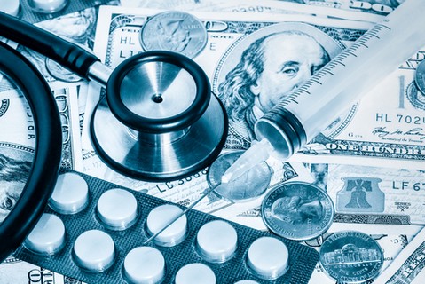 Stethoscope,pills,syringe over a stack of dollars